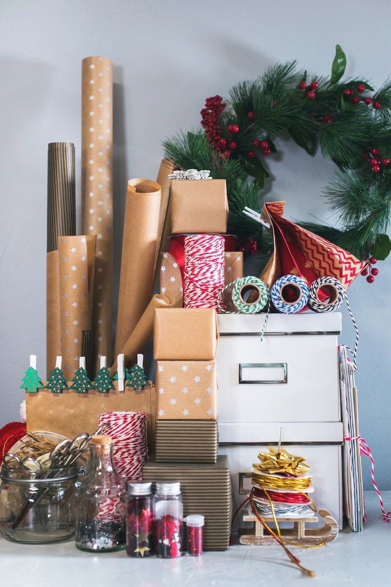 Packing boxes, gifts in kraft beige vintage wrapping paper. Wreath holly berry on gray wall background. Concept of preparation to New Year and Christmas holidays